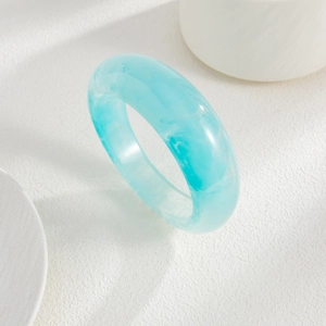 Detail view of light blue translucent acrylic bangle with marble pattern on a white stand