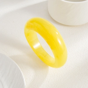 Detailed view of a bright yellow resin bangle with semi-transparent amber-like texture