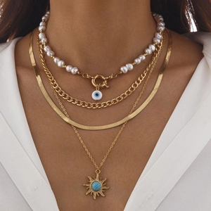 Nahaufnahme mehrlagiger Boho-Halsketten mit Perlen, Evil-Eye und Sonnenanhänger am Model