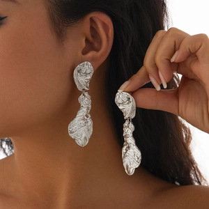 Gros plan de grandes boucles d'oreilles cœur en argent avec surface métallique froissée
