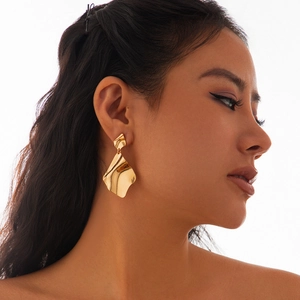 Detail von Model mit goldener unregelmäßiger geometrischer Ohrringe mit Wellentextur
