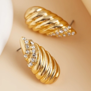 Detailaufnahme goldener Spiralohrringe mit Reihen aus funkelnden Kristallen