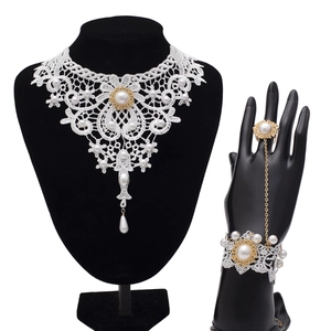 Detail von weißem Spitzen-Choker und passendem Ring-Armband mit Perlen und Goldakzenten
