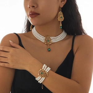 Detalle de conjunto de joyas vintage con gemas verdes, perlas de 4 capas y acabado oro