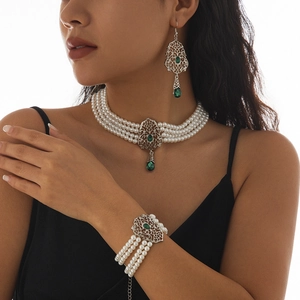Detalle del set de gargantilla de perlas multicapa con gema verde y metal estilo retro