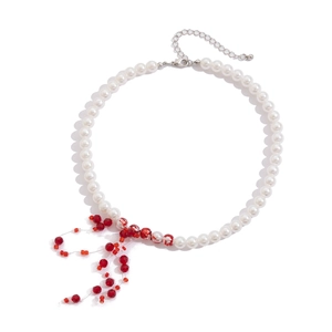 Macro shot of gothic pearl choker featuring red crystal beads and tassel drop accents