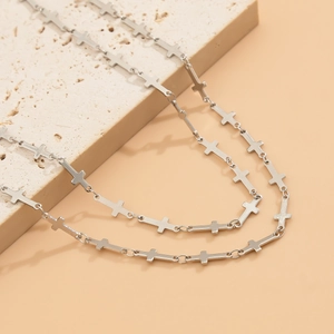 Detailed view of polished silver necklace with small cross elements on natural stone