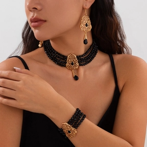 Detalle de conjunto de joyería vintage con cuentas negras y colgantes dorados