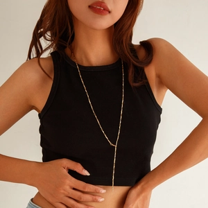 Detailed view of long gold Y-shaped necklace with minimalist cylinder chain on model