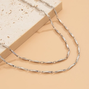 Detailed macro view of silver geometric twisted chain link necklace on stone