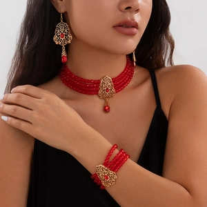 Detalle de conjunto de joyas con perlas rojas, colgantes dorados y cristales rojos