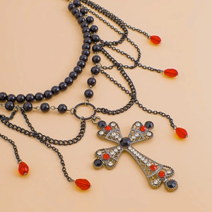 Detailaufnahme einer Gothic-Körperkette mit schwarzen Perlen und besetztem Kreuzanhänger