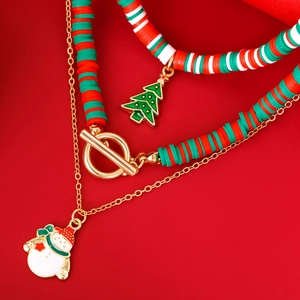 Macro-opname van gelaagde kerstketting met sneeuwpop en boomhangers op rode achtergrond