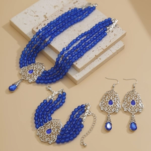 Detalle de conjunto de joyas de cuentas azules con pedrería cuadrada y toques plateados