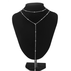 Detail of silver Y-shaped layered necklace with metallic beads on black display