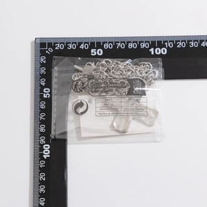 Detail van punk zilveren kruisketting met hanger met textuur en meetlat erbij