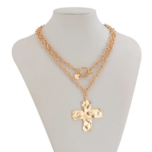 Detail van gouden gelaagde ketting met handgehamerde kruishanger en hartvormige bedel