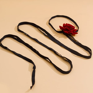 Detailed view of red velvet rose flower on long black ribbon for versatile styling