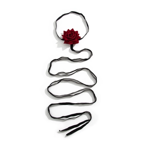 Detailed view of a dark red velvet rose choker with a long black silk ribbon strand