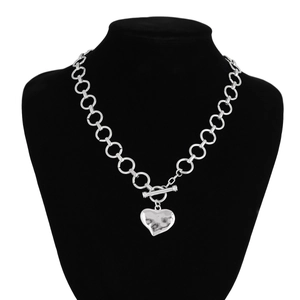 Detail van hartvormige hanger met hamerslagstructuur en zilveren OT-kapittelsluiting ketting