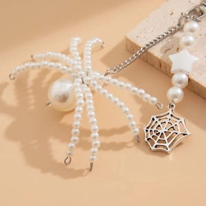 Close-up of spider keychain with large white pearls and a silver hollow spider web charm