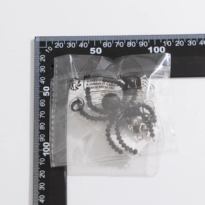 Detailed measurement of spider charm keychain in packaging with ruler for size reference