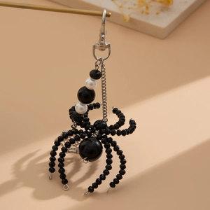 Detailed view of spider keychain featuring black faceted beads and white pearls