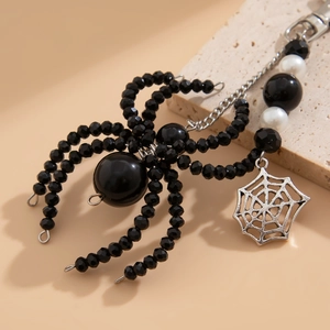 Detailed view of a black beaded spider charm with a silver hollow spider web pendant