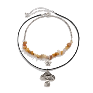 Detail van gelaagde ketting met paddenstoel hanger, ster en oranje stenen kralen