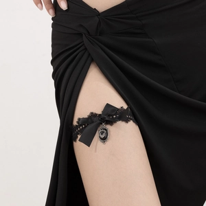 Detail eines schwarzen Oberschenkelrings aus Spitze mit Satinschleife und Gothik-Anhänger