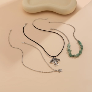 Detail van gelaagde ketting met paddenstoelhanger, ster en groene kralenstreng