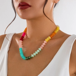 Nahaufnahme einer Regenbogen-Acryl-Perlenkette an einem Model im weißen Top