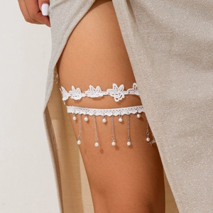 Detailaufnahme des weißen Spitzen-Strumpfbands mit Silberketten und Perlen