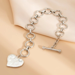 Dettaglio del bracciale a catena d'argento con pendente a cuore martellato su raso