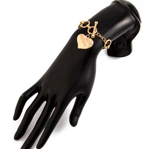 Dettaglio del bracciale a catena spessa dorata con ciondolo a cuore e chiusura a levetta