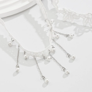 Makroaufnahme von weißem Spitzen-Choker mit silbernen Quasten und Perlenanhängern