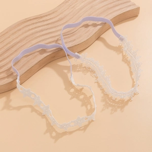 Detail eines weißen Spitzenbandes mit lavendelfarbenem Gummiband auf Holzbrett