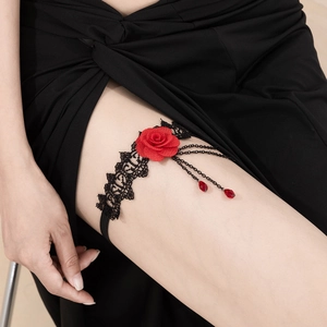 Détail de jarretière avec rose rouge, dentelle noire et fines chaînes en métal
