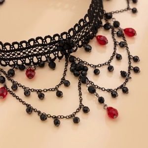 Close-up of gothic black lace choker with red teardrop beads and tassel chains