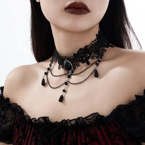 Macro detail of gothic lace choker featuring a black crystal and hanging metal chains