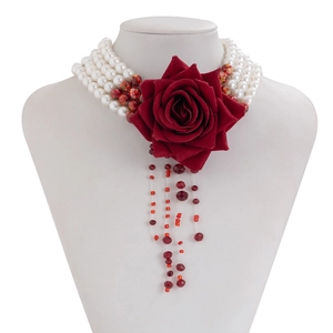 Detail of multilayer pearl choker with red fabric rose and dripping fringe on a white bust