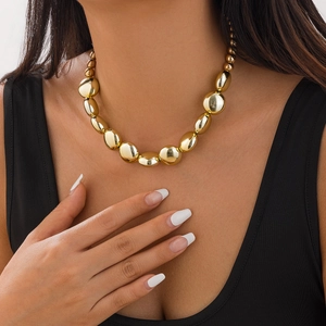 Gros plan d'un collier ras du cou à billes dorées porté par un mannequin pour un look rétro