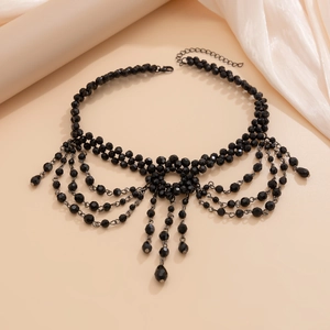 Detail of black layered tassel necklace with faceted beads and cross pendant