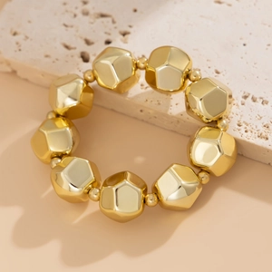 Conjunto de collar y pulsera de cuentas doradas facetadas sobre fondo de piedra natural