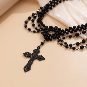 Macro view of gothic black beaded necklace featuring a large filigree cross pendant