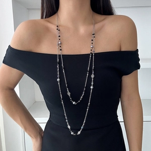 Detail of layered silver beaded long necklace on model in black off-shoulder dress