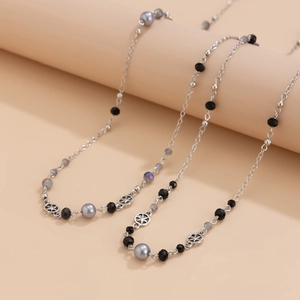 Elegant long pearl necklace with silver accents and gray beads draped on a display
