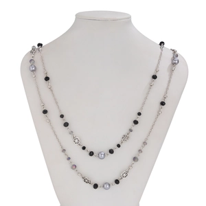 Detailed view of layered beaded necklace with grey pearls and silver hollow metal charms