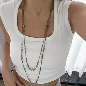 Detail of layered bohemian necklace featuring grey beads and gold floral accents