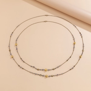 Detail of vintage long chain necklace featuring blue crystal beads and golden flower charms